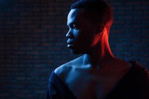 Confident guy. Futuristic neon lighting. Young african american man in the studio photo