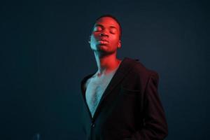 Confident and serious. Futuristic neon lighting. Young african american man in the studio photo