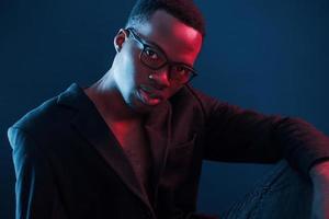 Fashion model. Futuristic neon lighting. Young african american man in the studio photo