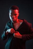 Confident and serious. Futuristic neon lighting. Young african american man in the studio photo