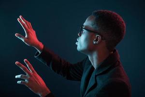 Hands in front. Futuristic neon lighting. Young african american man in the studio