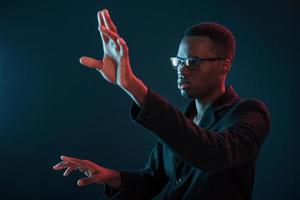 Hands in front. Futuristic neon lighting. Young african american man in the studio photo
