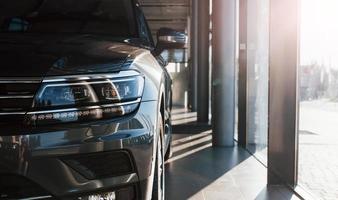 Front part of brand new modern car. Parked at showroom. Reflection in the headlights photo