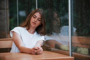 retrato de una joven que se sienta en un café en un día lluvioso. una sola persona