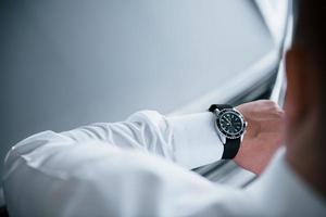 Close up photo of man's hand in suit with luxury watch near the car