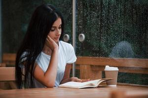 retrato de una joven estudiante que se sienta en un café en un día lluvioso. una sola persona