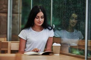 Portrait of young female student that sits in cafe at rainy day. One person only photo