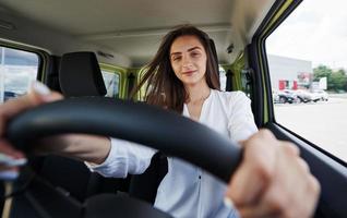 Happy owner. Front view of woman that drives modern new car in the city photo