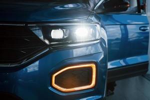 Front part of brand new modern blue car. Parked at showroom. Reflection in the headlights photo