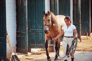 Getting ready for the ride. Horsewoman in white uniform with her horse at farm. Ready for the ride photo