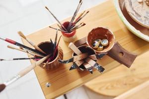 Top view of brushes and other pottery tools that is on the wooden table photo