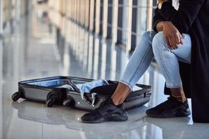 Particle view of young african american female passanger in casual clothes that in airport with baggage photo
