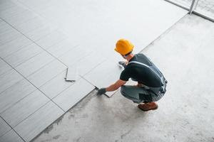 Top view of man in grey uniform that installing plate indoors in modern big office at daytime photo