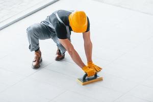 Top view of man in grey uniform that installing plate indoors in modern big office at daytime photo