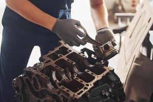 Professional repairman works with broken automobile engine photo