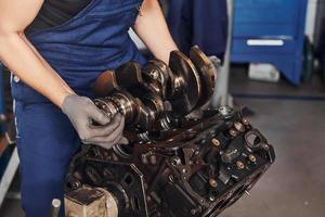 Professional repairman in garage works with broken automobile engine photo