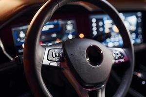 Steering wheel and navigation display. Close up view of front park of new modern black automobile photo