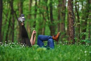 Couple lying down on the grass in forest together at daytime photo