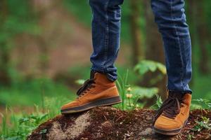 Close up view of man's legs on the rock in forest. Traveler have a walk photo