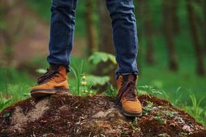 Close up view of man's legs on the rock in forest. Traveler have a walk photo
