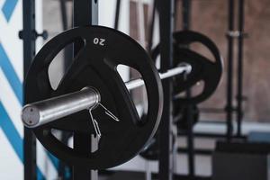 concepción de la fuerza. barra negra en el soporte de metal en el gimnasio durante el día. sin gente alrededor foto