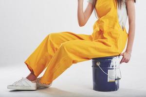 Particle view. Brunette woman in yellow uniform sits against white background in the studio photo