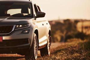 Blurred background. Modern new car parked on the side road at countryside at daytime photo