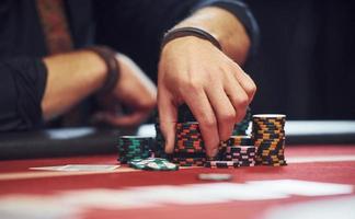 Close up view of man's hands. Guy plays poker game by table in casino photo