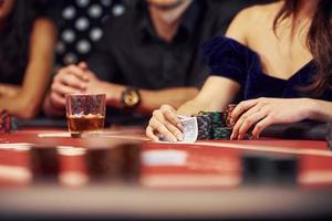 con vasos de bebida. grupo de jóvenes elegantes que juegan al póquer en el casino juntos foto