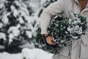 Young handsome man carrying fresh cutted fir tree outdoors photo