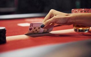 Close up view of woman's hands. Girl plays poker game by table in casino and checks cards photo