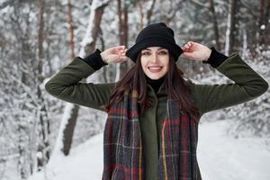 es un estado de ánimo juguetón. una joven alegre con ropa de abrigo da un paseo por el bosque de invierno durante el día