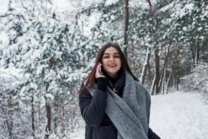 Cherful brunette have conversation while have a walk in winter forest photo