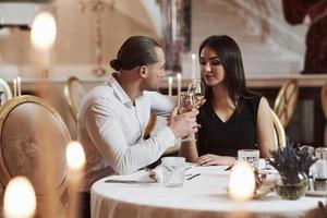 el chico hace una fiesta para la chica. una pareja hermosa tiene una cena romántica en un restaurante de lujo por la noche foto