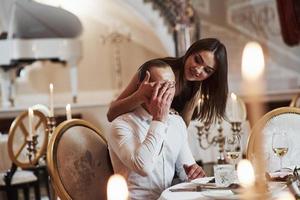 Surprise, guess who. Beautiful couple have romantic dinner in luxury restaurant at evening time photo