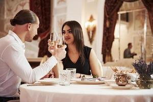 Satisfied youth. Beautiful couple have romantic dinner in luxury restaurant at evening time photo