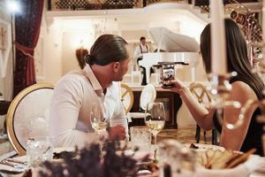 conversación entre pareja y músico. una pareja hermosa tiene una cena romántica en un restaurante de lujo por la noche foto