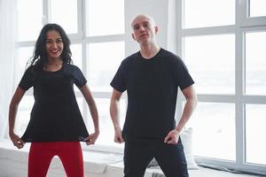 Man and woman in black shirts standing in the room near the windows photo