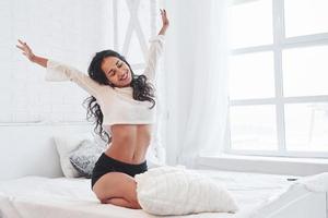 Morning stretch. Brunette having a rest on the white couch in her bedroom at daytime photo