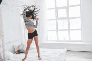 Dancing on the white bed. Brunette having fun on their weekend time photo