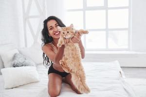 creo que puedo volar. rubia atractiva descansando en la cama blanca con su lindo gatito foto