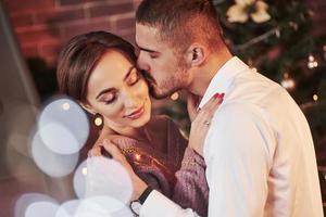 Kiss in the cheek. Nice couple celebrating new year in the new year decorated room photo