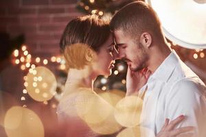 In magical lightings. Nice couple celebrating new year indoors with classic beautiful clothes on them photo