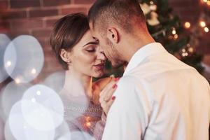 With eyes closed. Nice couple celebrating new year in the new year decorated room photo