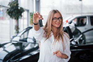 Proud owner. Young manager in the auto shop stands against perfectly polished black car photo