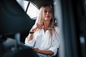 Some deals is coming. Smart businesswoman sits at backseat of the luxury car with black interior photo