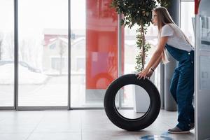 Cold weather outside. Woman walks with brand new wheel to the car. Conception of repair photo