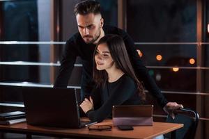 Bearded modern looking guy. Team of young business people works on their project at night time in the office photo