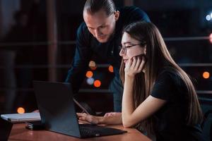 Your help needed. Team of young business people works on their project at night time in the office photo