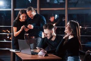 Resting and laughing. Team of young business people works on their project at night time in the office photo